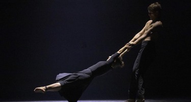 Male dancer swinging female dancer by arms.