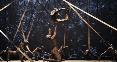 Dancer arches back while jumping to be caught by kneeling man.