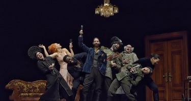 Group of dancers in period Russian and military dress with chandelier.