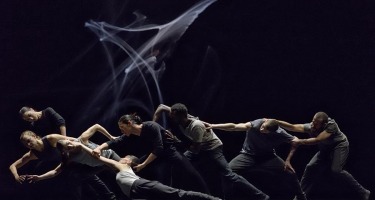 Group of dancers pulling each other in unison.