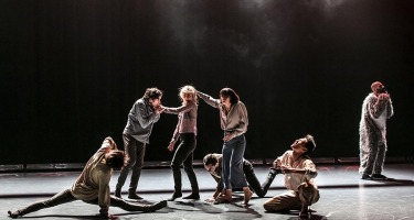 Group of dancers on left side with one dance in plush costume on right.