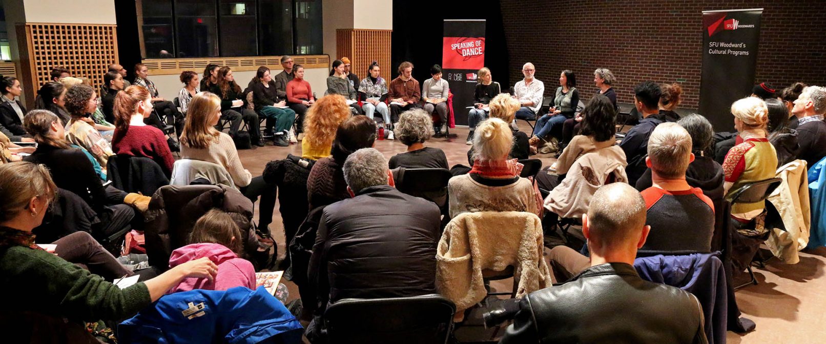 Speaking of Dance. Room full of people sitting in a circle on chairs about three rows deep.