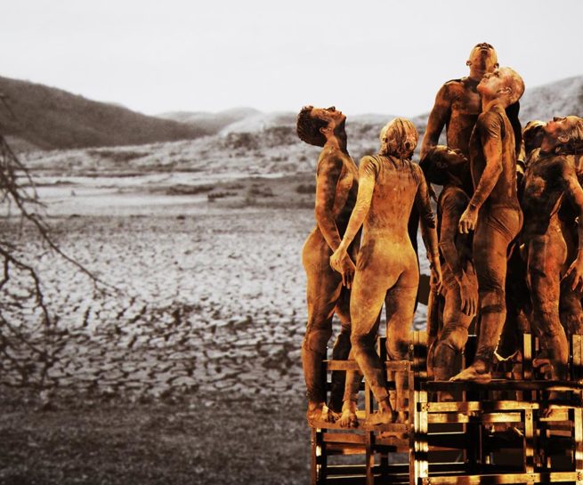 Group of dancers on ladder-like structure with projection of tree and roots in background.